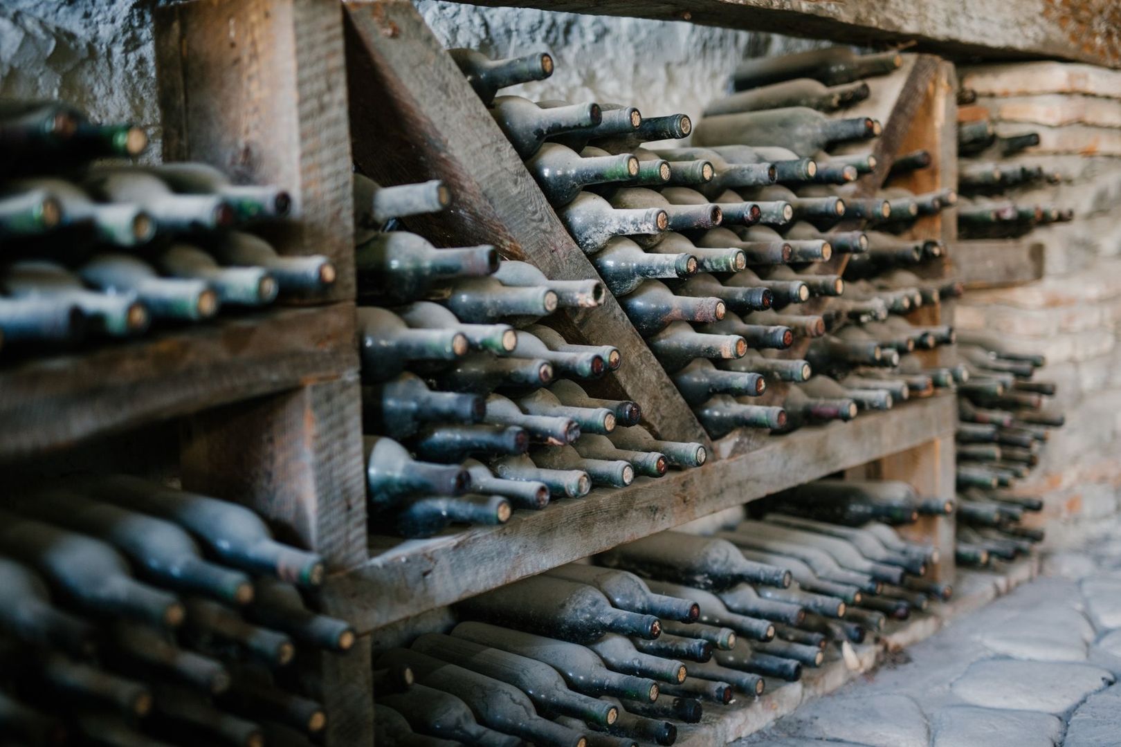 Bouteilles de vin vieillissant horizontalement dans une cave en pierre
